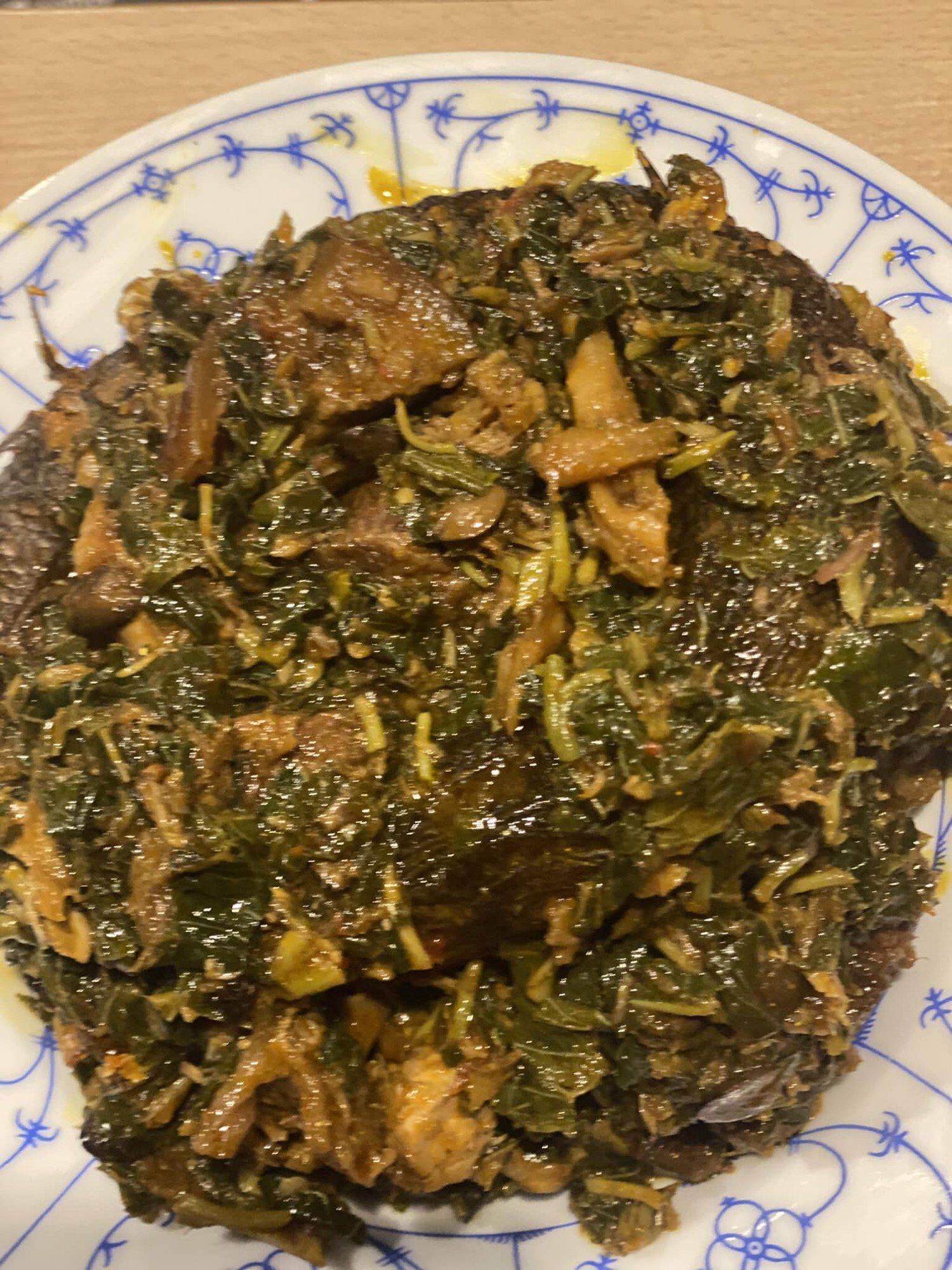 Leafy green soup with meat on a blue-patterned plate