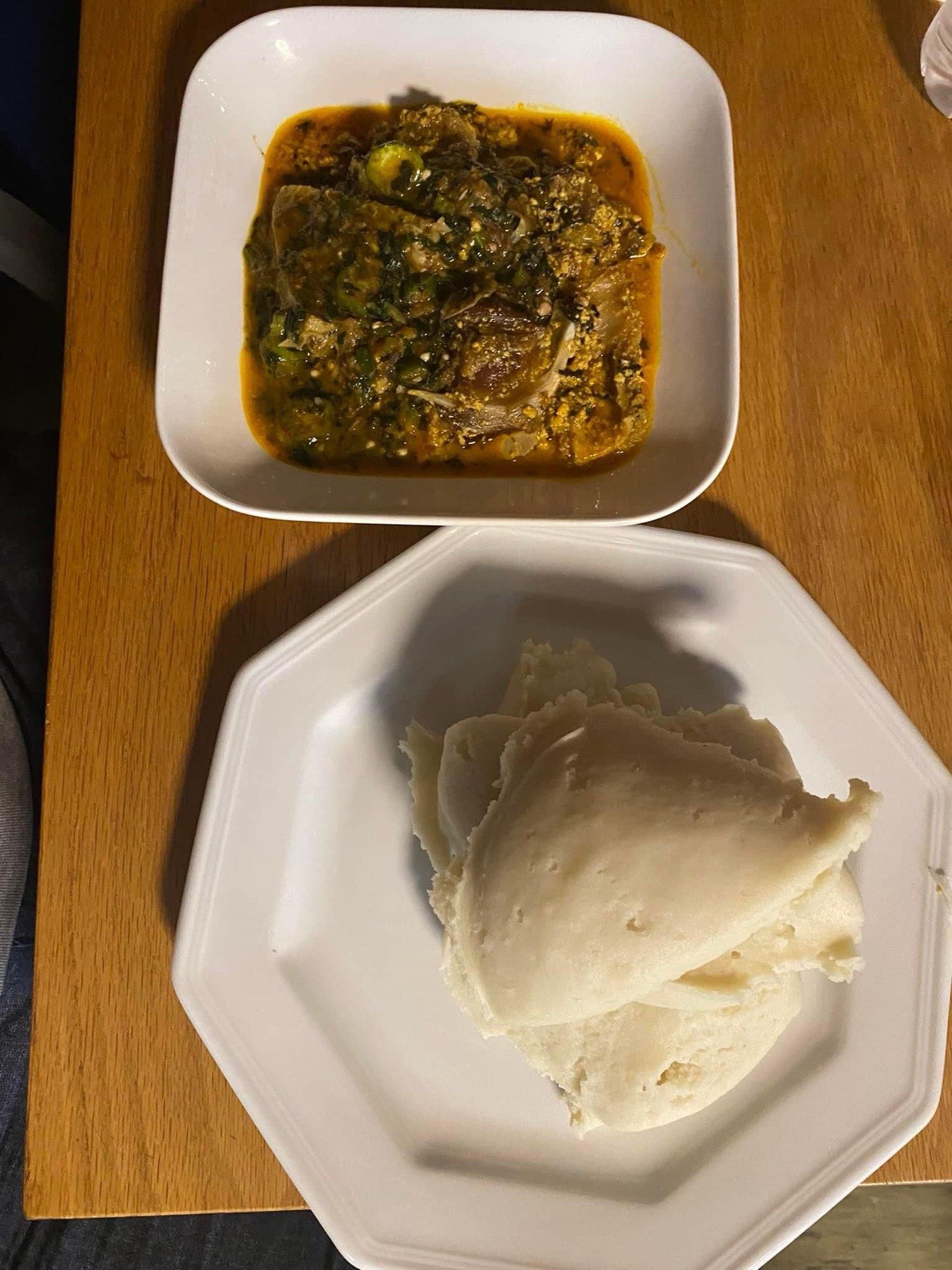 Okra soup in a white dish next to a portion of swallow