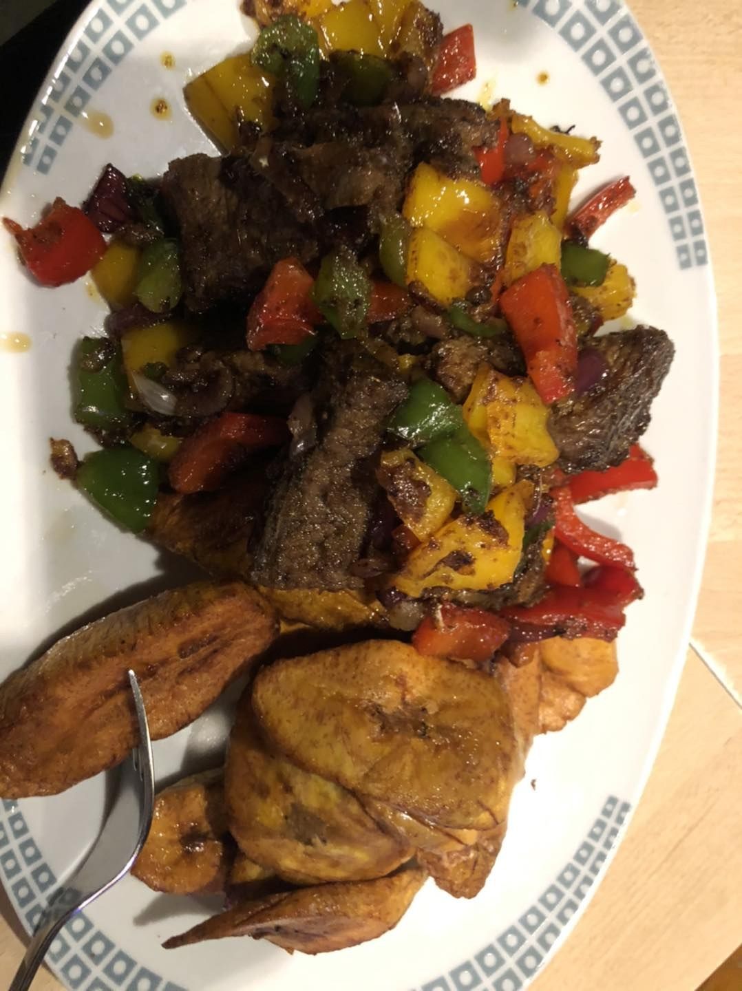 Peppered meat with onions and bell peppers beside fried plantain