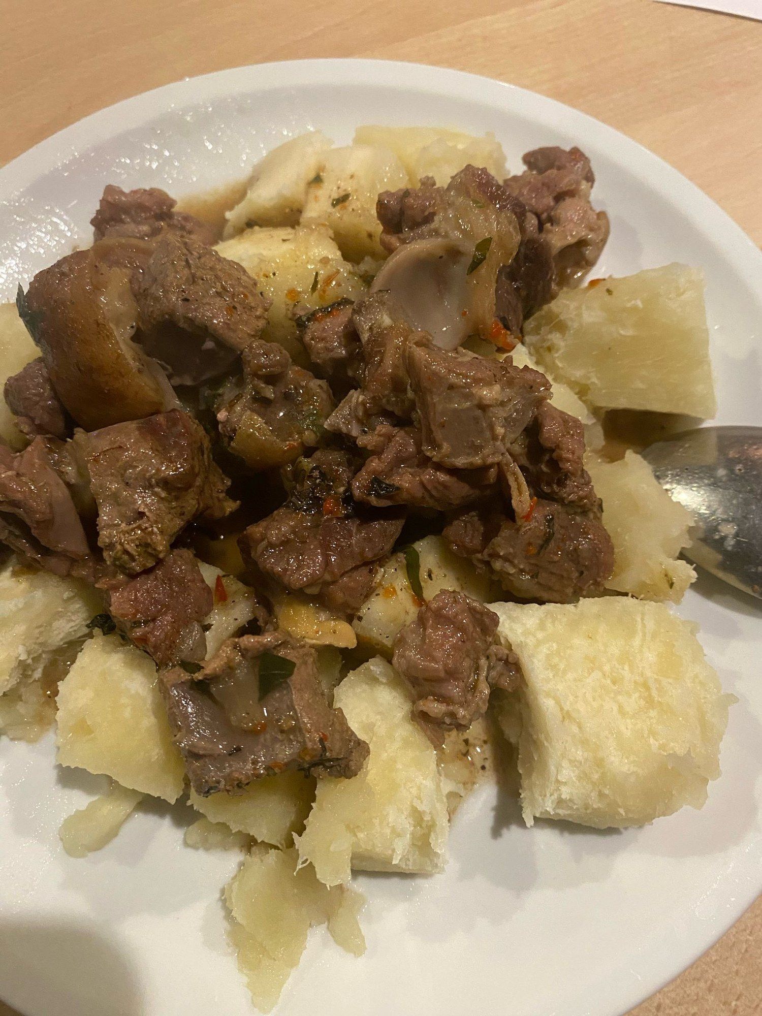 Boiled yam with meat and onions on a white plate